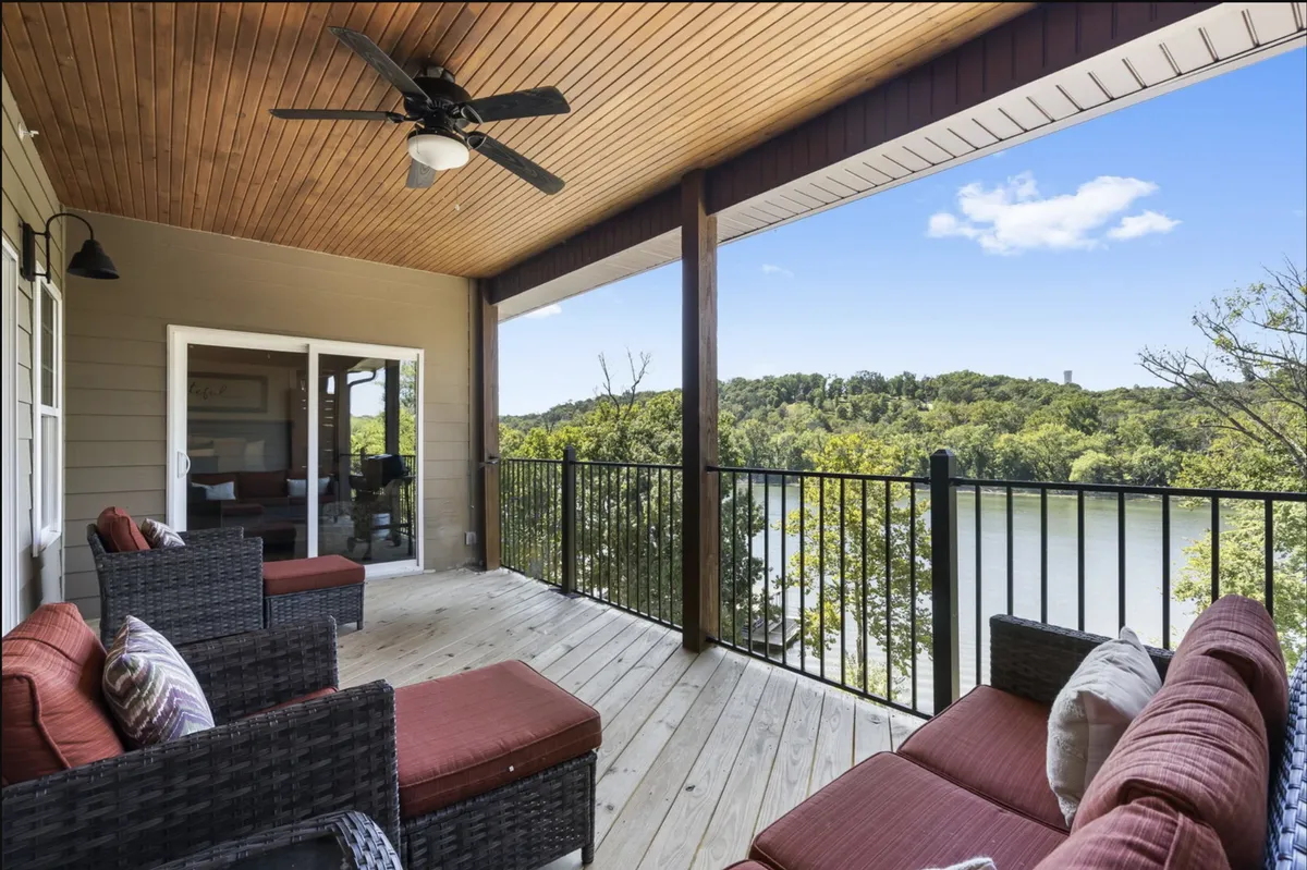 This exterior shot features a tranquil deck with comfortable seating overlooking the river, framed by a wooden ceiling. It evokes the experience of sipping morning coffee or evening drinks while enjoying panoramic lake views.