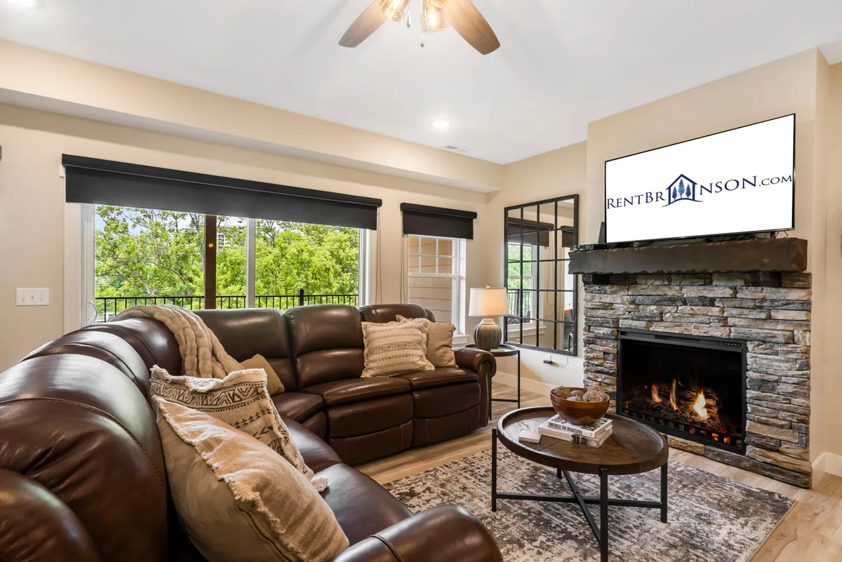 This cozy living room features a leather sofa, fireplace, TV, and coffee table, with soft lighting that enhances the warm, inviting atmosphere. Large windows or a balcony suggest a connection to the outdoors—ideal for unwinding after a day outside or watching the sunset from inside.